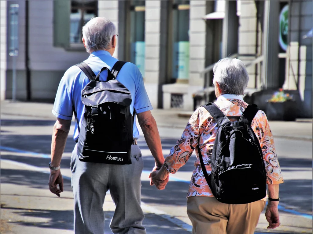 Una pareja mayor caminando con mochilas en una ciudad